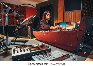 Young Woman Music Producer Working On A Mixing Soundboard While In Her Studio