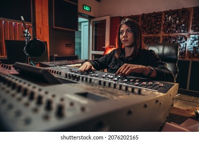 Young Woman Music Producer Working On A Mixing Soundboard While In Her Studio