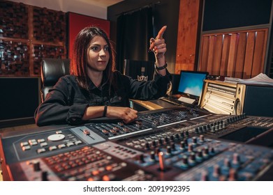 Young Woman Music Producer Working On A Mixing Soundboard While In Her Studio