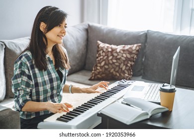 Young Woman Music Teacher Playing Electric Piano Teaching Remotely Using Laptop While Working From Home. Online Education And Leisure Concept.