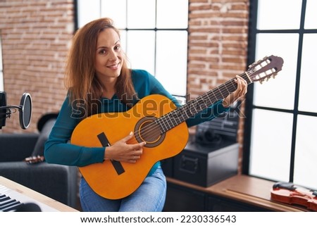 Young woman musician playing classical guitar at music studio