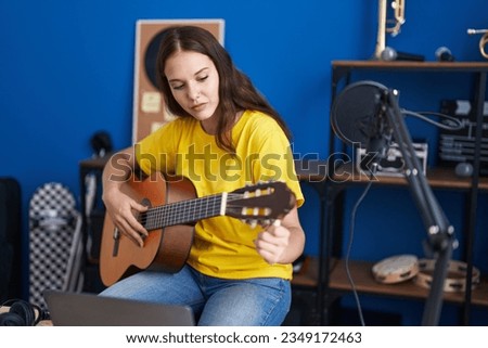 Young woman musician playing classical guitar at music studio