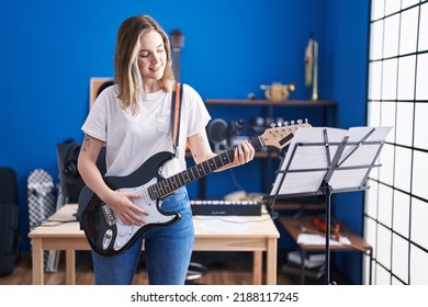 Young Woman Musician Playing Electrical Guitar At Music Studio