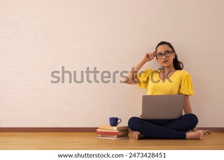 A young woman musing while working on her laptop.