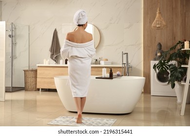 Young woman near tub in bathroom, back view