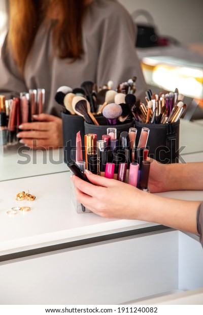 Young woman\
is neatly organizing her lipstick, lip gloss in the makeup storage\
and putting into dressing table drawer. Concept of storing personal\
makeup beauty product in\
organizer.