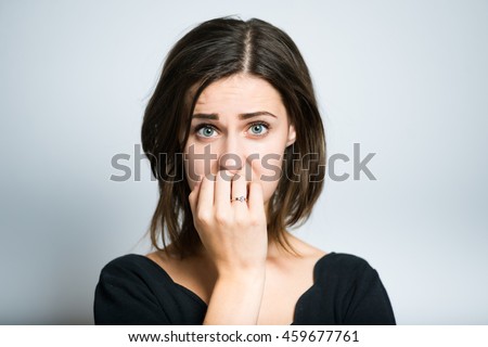 young woman nervous and bites nails, studio photo isolated on a gray background