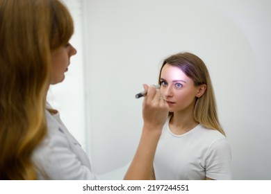 Young Woman In Neurologist Appointment. Female Doctor Checks Eyes Reflexes With Flashlight