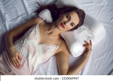 Young Woman In A Nightgown Lying In A White Bed On The Pillow