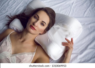 Young Woman In A Nightgown Lying In A White Bed On The Pillow