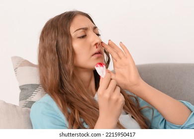 Young Woman With Nosebleed And Tissue At Home, Closeup