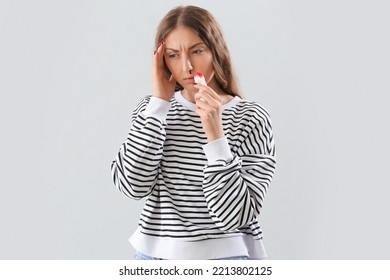 Young Woman With Nosebleed And Tissue On Light Background