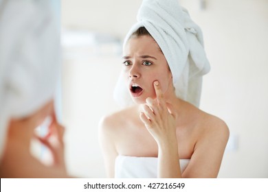 Young Woman Noticing A Pimple On Her Face In Terror