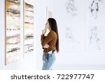 Young woman observing painting while visiting art gallery with famous artist collection