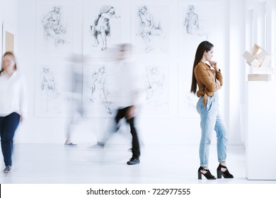 Young Woman Observing Sculpture In Modern Art Gallery With Drawings. Art Gallery Concept 