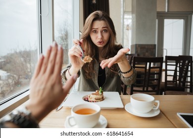 Young Woman Offering Cake To Her Friend And Last One Refusing