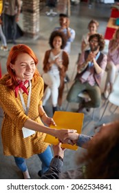 The young woman at office meeting in a pleasant atmosphere is shaking hands with a colleague after receiving congratulations for merit at work. Employees, office, work - Shutterstock ID 2062534841