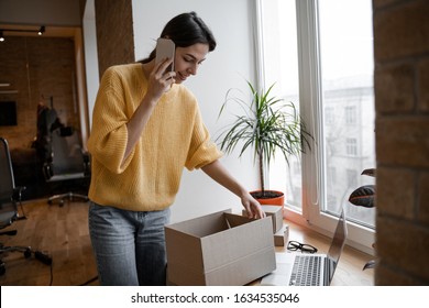Young woman office worker employee of a company manufacturing products and selling on the Internet talking on the phone, work process, packing goods for delivery - Shutterstock ID 1634535046