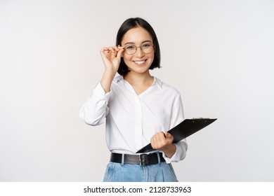 Young Woman, Office Worker Manager In Glasses, Holding Clipboard And Looking Like Professional, Standing Against White Background