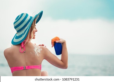 Young Woman On Beach Applying Sun Block Creme