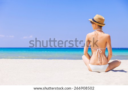 Young woman on the beach. Girl sitting on sand and sunbathing. Relaxation, rest, vacations, holidays, summer fun, enjoy life concept