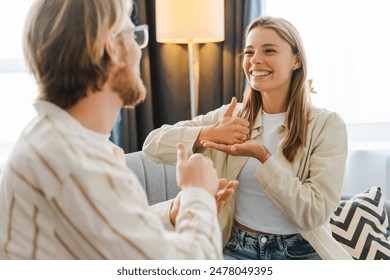 Young woman on a cozy couch signs with her therapist, showing empathy and connection in mental health counseling. The therapist listens attentively, creating a safe space. Sign language concept