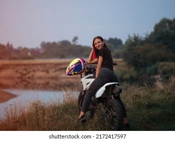 A Young Woman On A Cross - Country Motorcycle Or Pit Bike At Sunset . Active Recreation