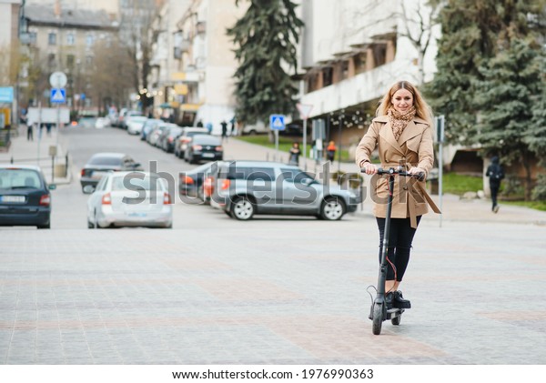 Young woman on electro\
scooter in city.
