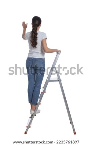 Young woman on metal ladder against white background, back view