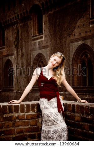 Young woman on old building background. Dark red tint.