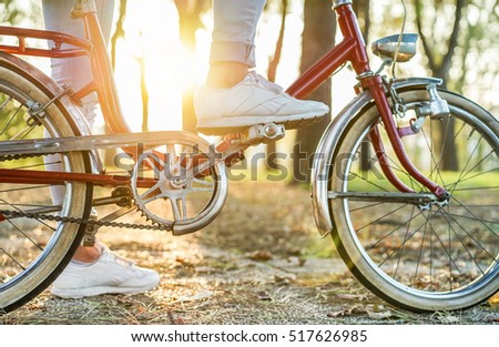 Young woman on old style italian bicycle with back light - Close up of girl feet riding vintage bike in park outdoor for fall time - Vintage fashion concept - Focus on top foot - Warm retro filter
