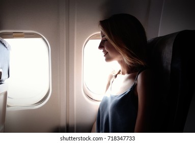 Young Woman On Passenger Seat Near Window In Airplane