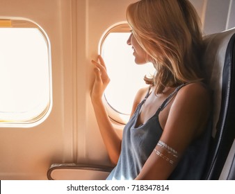Young woman on passenger seat near window in airplane