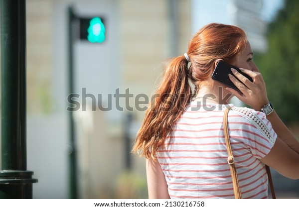 young woman on the\
phone crossing the street