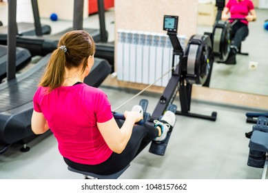 Young Woman On Rowing Machine In Gym