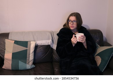 Young Woman On Sofa In Dressing Gown With Mug