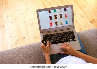 Young Woman On Sofa Make Shopping Online On Fake Website With Fake Credit Card And Buying Dress