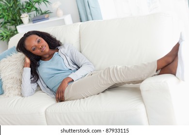 Young Woman On Sofa Putting Her Feet Up