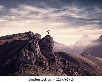 Young woman on top of a mountain with her arms raised.
