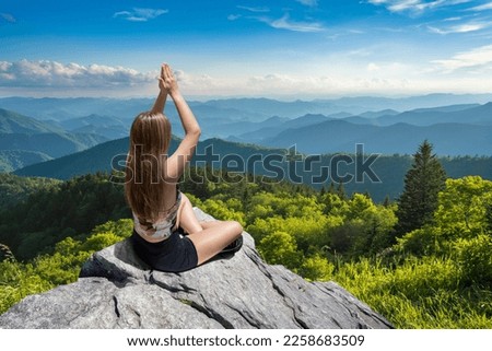 Young woman on the top of mountain meditating. Young woman practicing yoga in nature. Blue Ridge Mountains, near Asheville, North Carolina, USA.