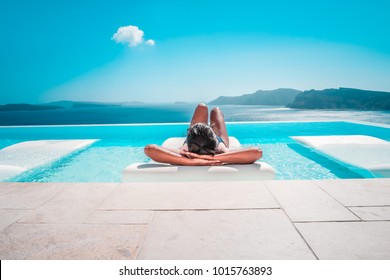 Young woman on vacation at Santorini, women at the swimming pool looking out over the Caldera ocean of Santorini, Girl at the infinity pool Oia Santorini Greece - Powered by Shutterstock