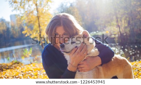 Young woman on a walk with her dog breed Akita inu. Girl on a walk hugs her beautiful dog