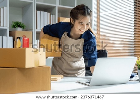 Young woman online business owner is using laptop to prepare the package for delivery to the customer