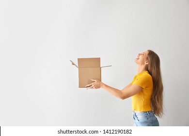 Young Woman With Open Cardboard Box On Light Background