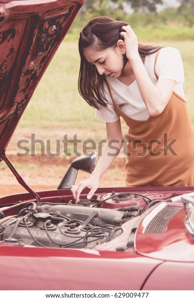 Young woman open hood a car and checking engine on\
his car.