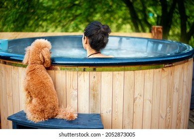 Young woman in an open-air bath with a view of the mountains. Young woman with her dog. - Powered by Shutterstock