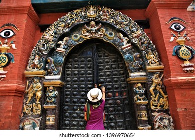 
The young woman is opening a beautiful old wooden palace door to visit the Nepal palace.