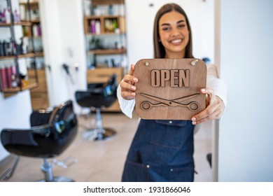 Young Woman Opening A Beauty Store And Looking Very Happy - Small Business Concepts. Smiling Owner Of Hair Salon Standing With Sign Open And Leaning On Glass Door