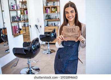 Young Woman Opening A Beauty Store And Looking Very Happy - Small Business Concepts. Smiling Owner Of Hair Salon Standing With Sign Open And Leaning On Glass Door