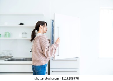 Young Woman Opening A Door Of A Refrigerator.